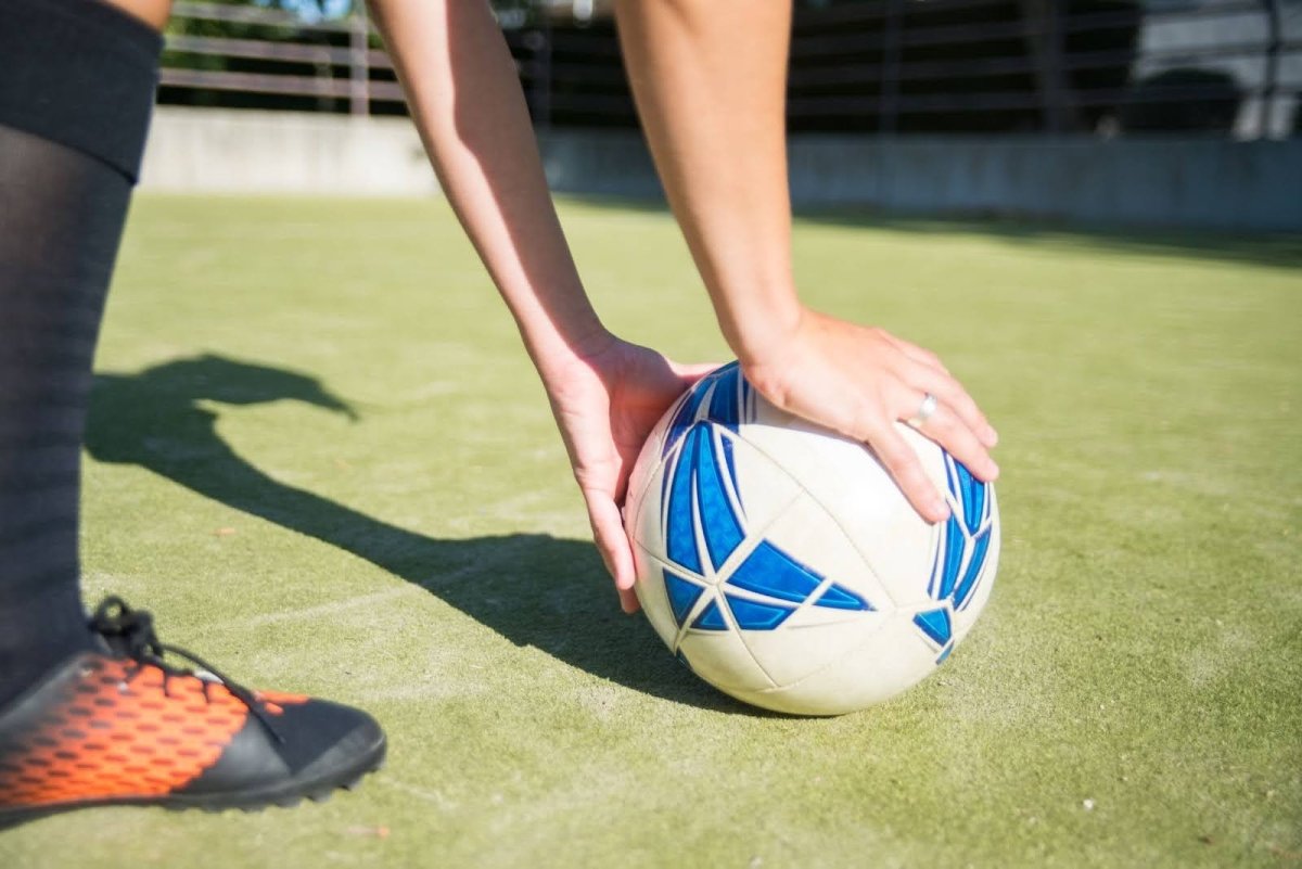 Player putting a training soccer ball on the ground.